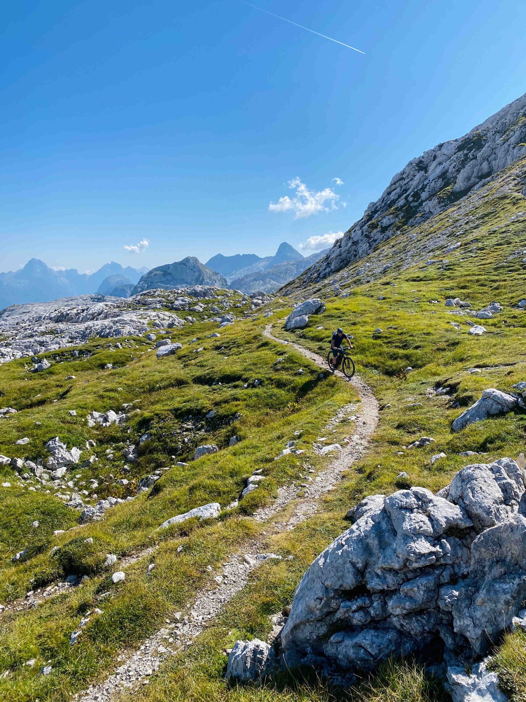 Cyclist riding down a trail in mountainous terrain
