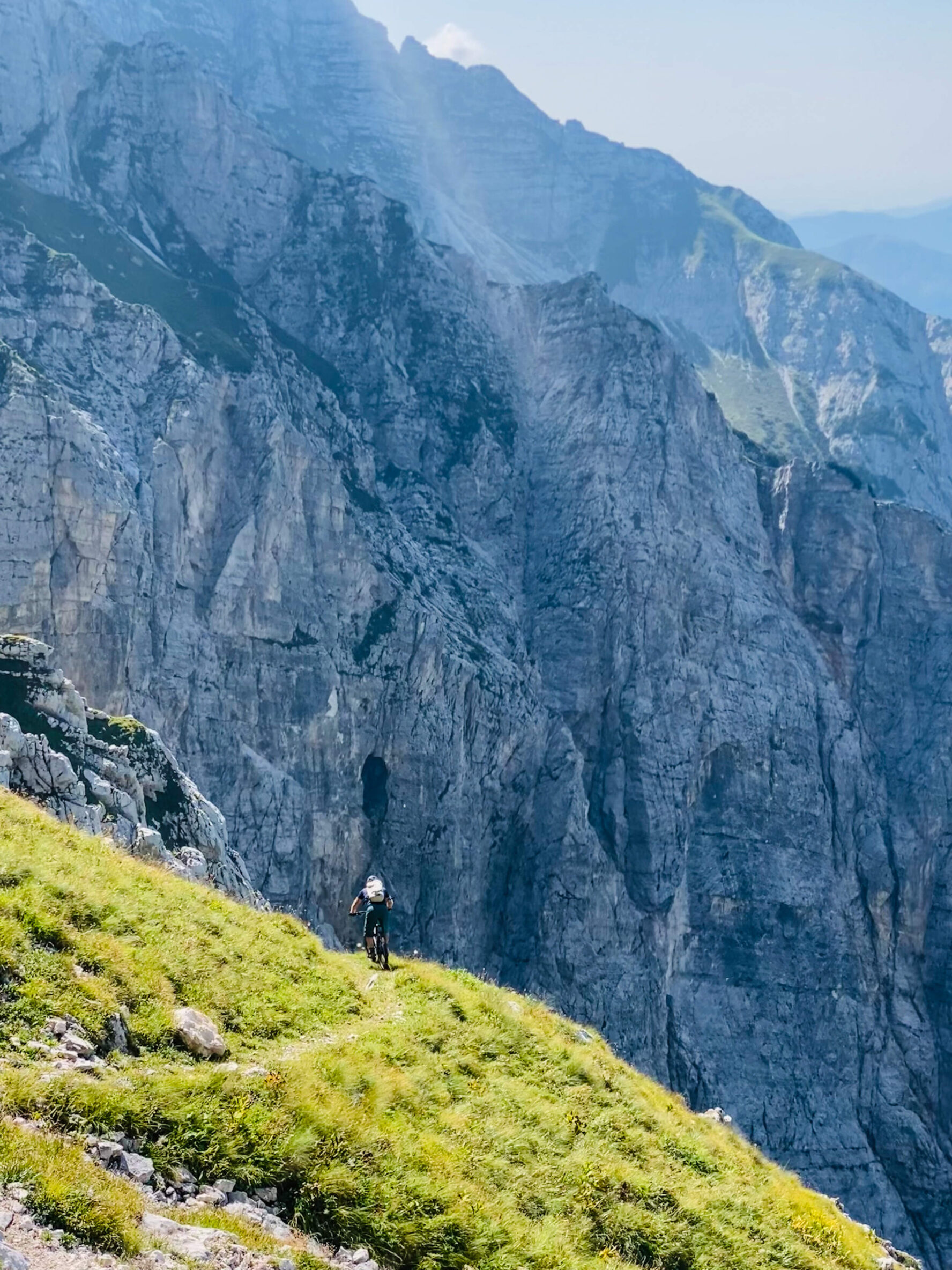 Cyclist on a trail with a towering rocky mountain backdrop