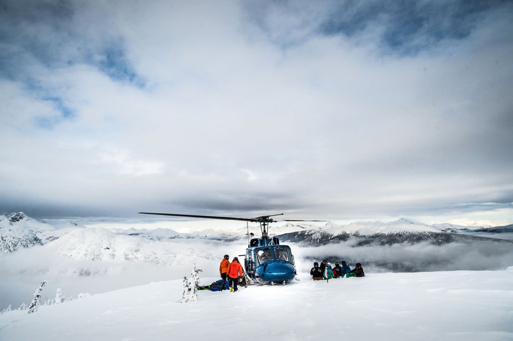 Helicopter on snowy mountain with skiers preparing for flight