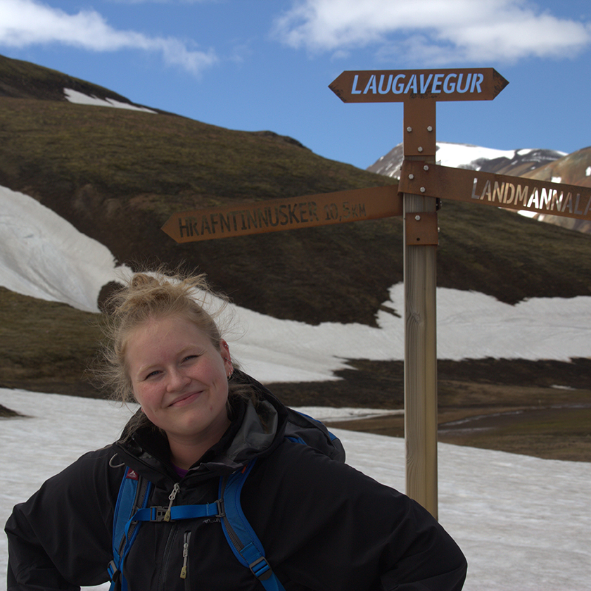 Hiker smiling next to Landmannalaugar signpost