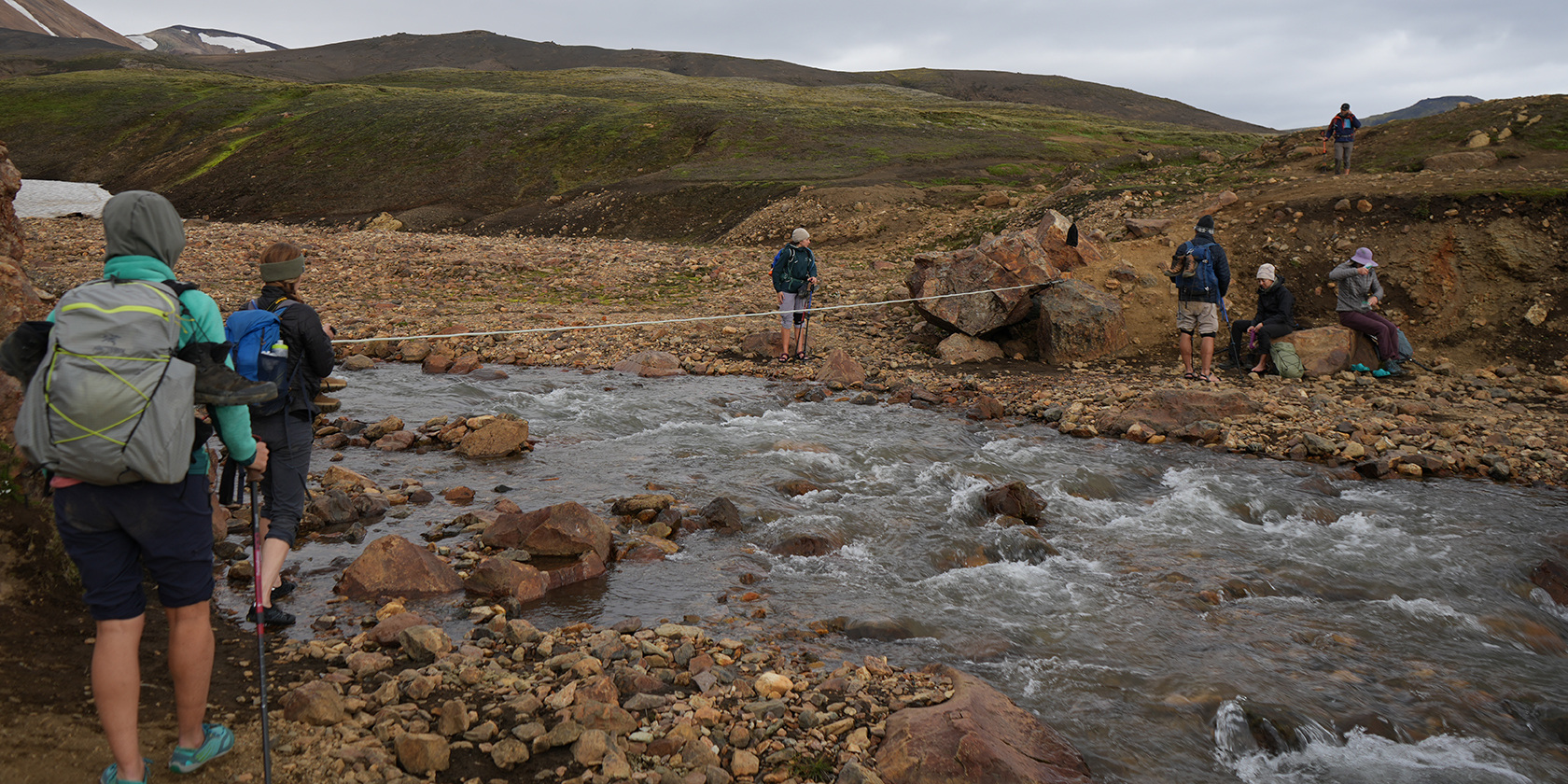 Hikers crossing a rocky stream in Landmannalaugar