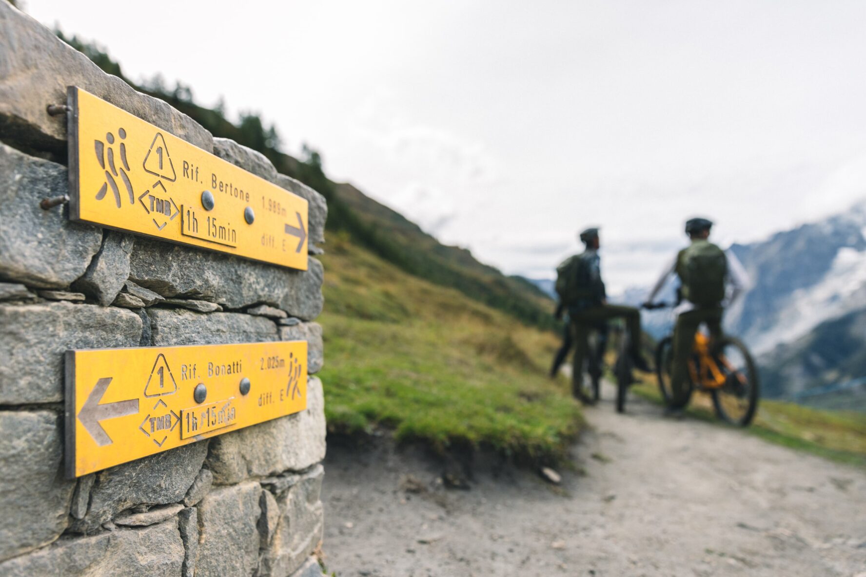 A signpost in the Mont Blanc area with riders in the backdrop