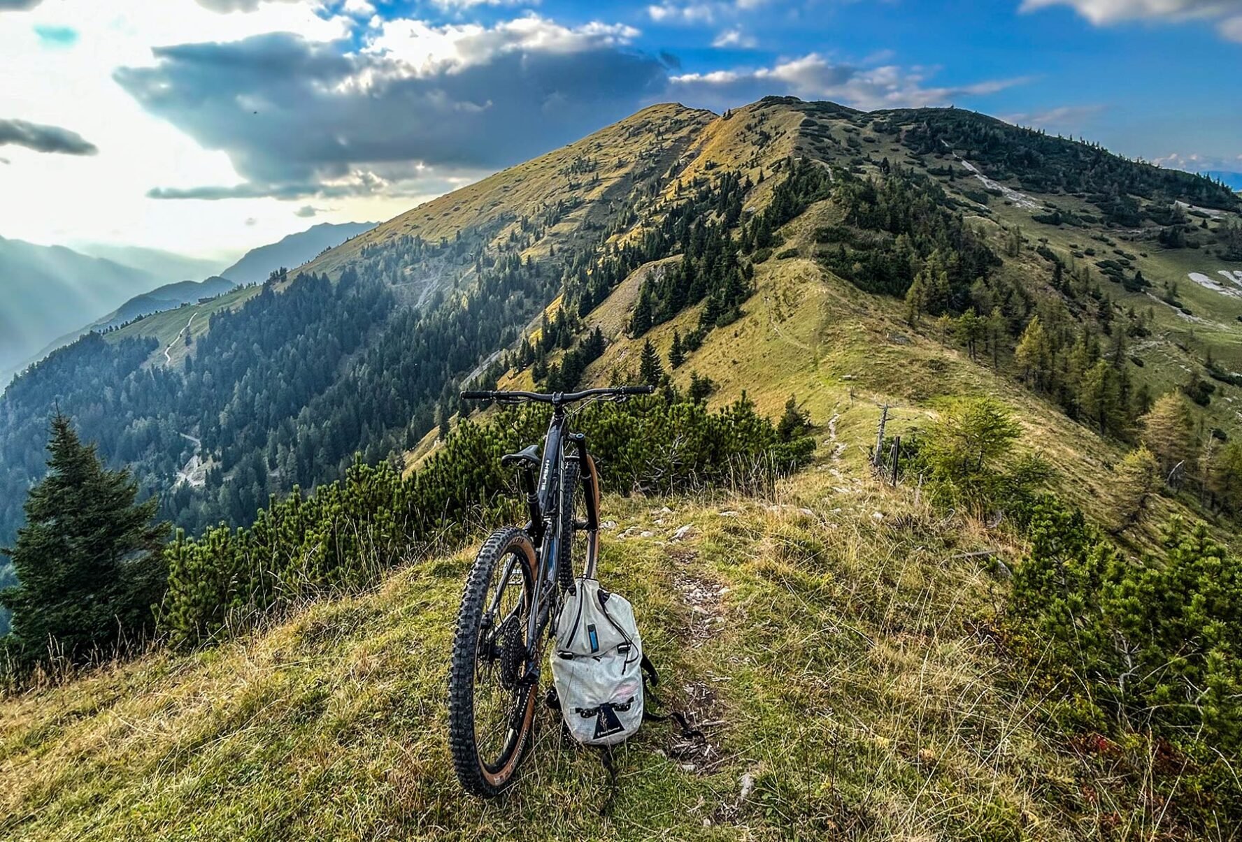 MTB and backpack on a hill overlooking a forested landscape