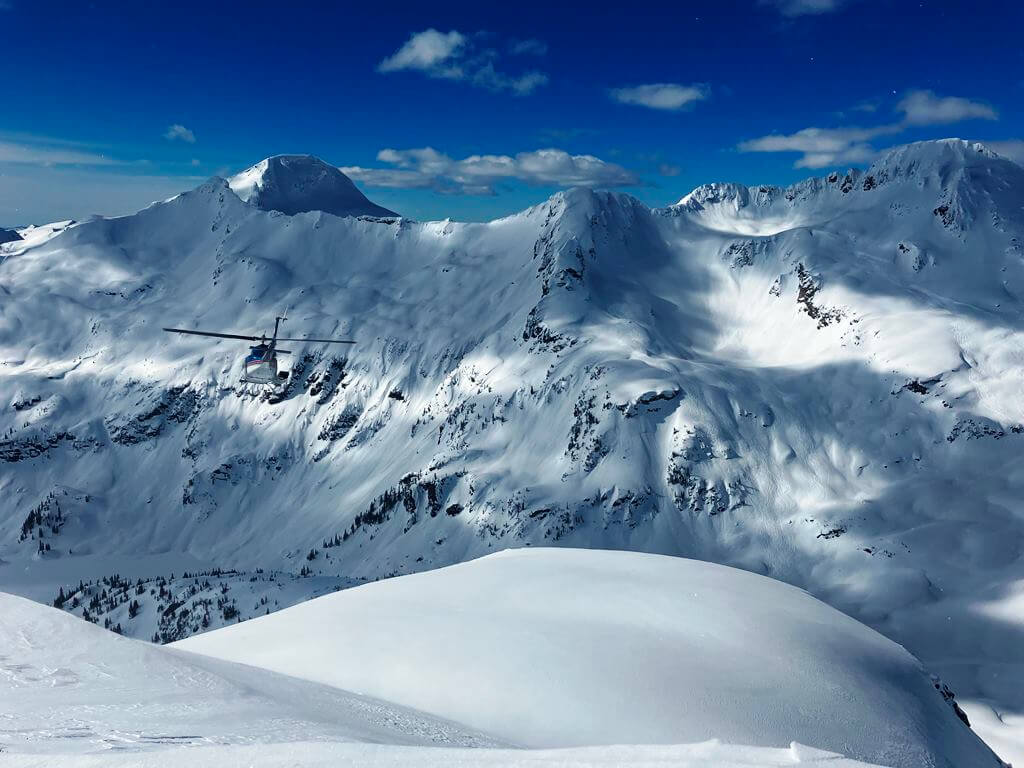 Helicopter flying above snow-capped mountains