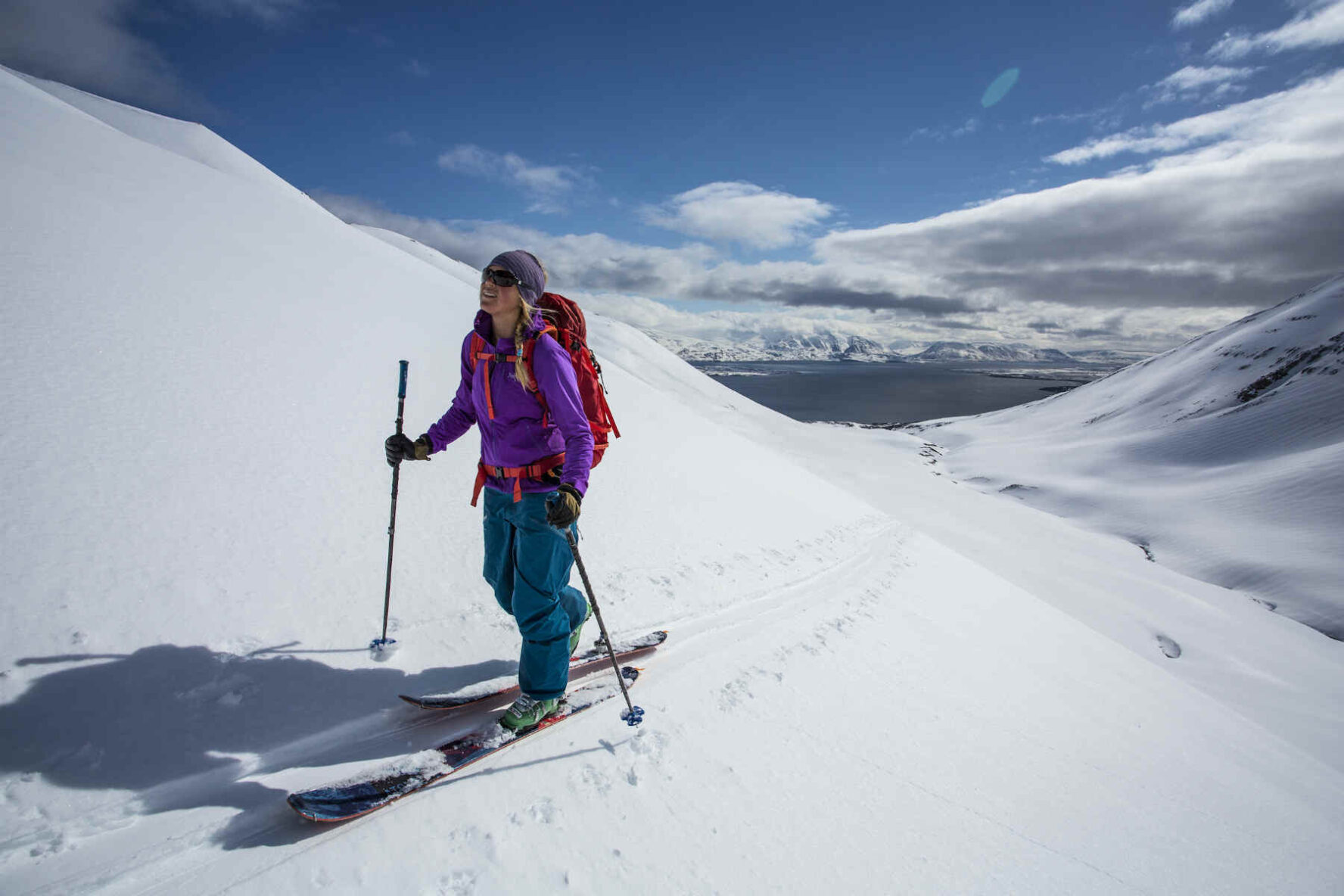 A skier touring snowy slopes with a fjord in the distance