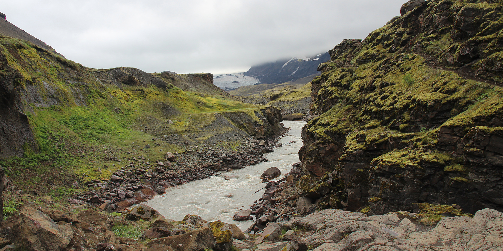 Thorsmork valley with moss-covered cliffs, a river, and a glacier