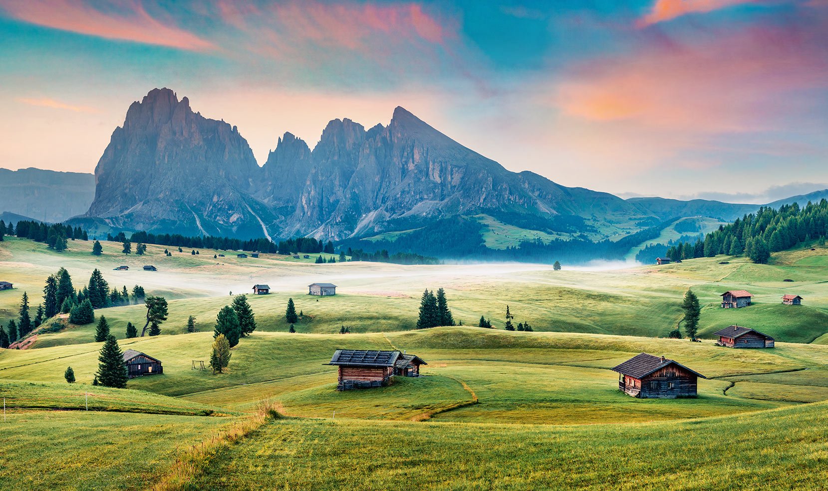 Wooden huts and the Dolomites at dawn