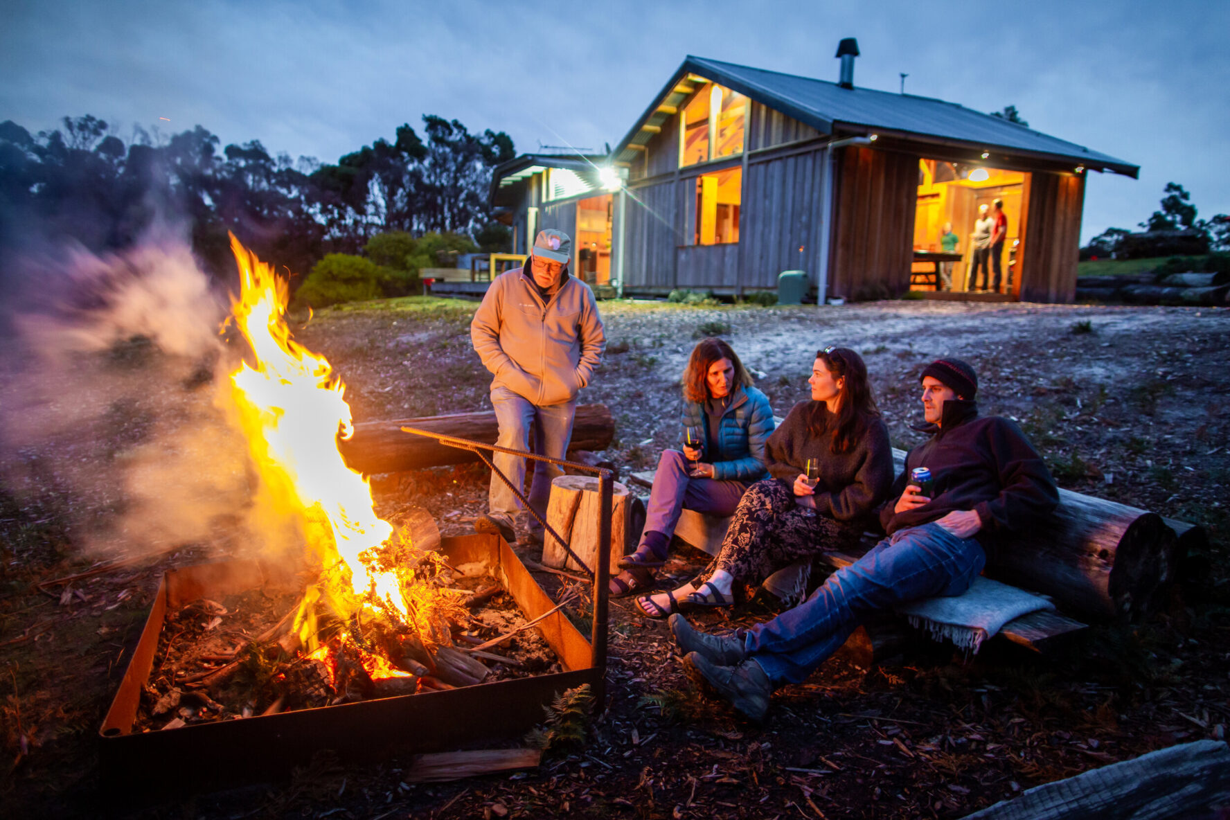Group hanging out around a bonfire in front of Bruny Island Lodge