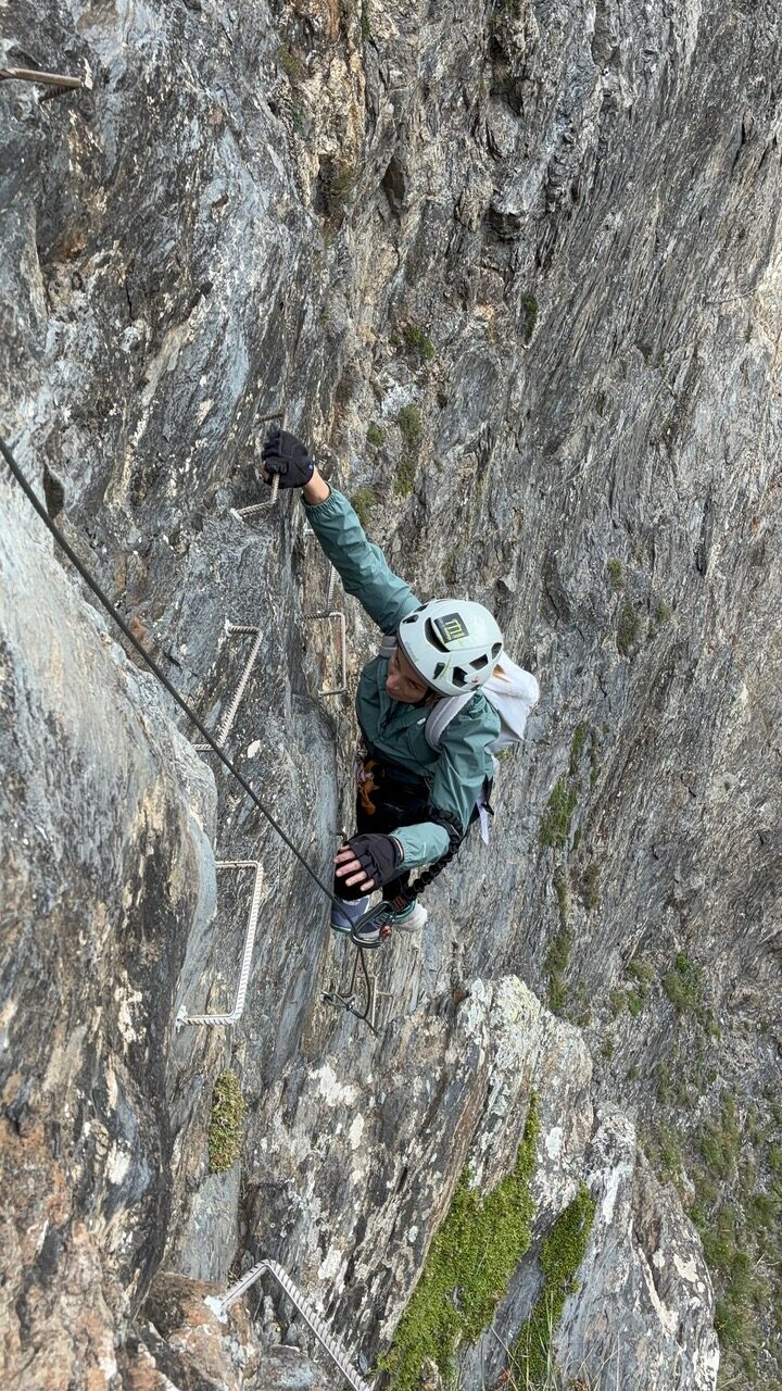 Climber scaling a rock face with metal rungs