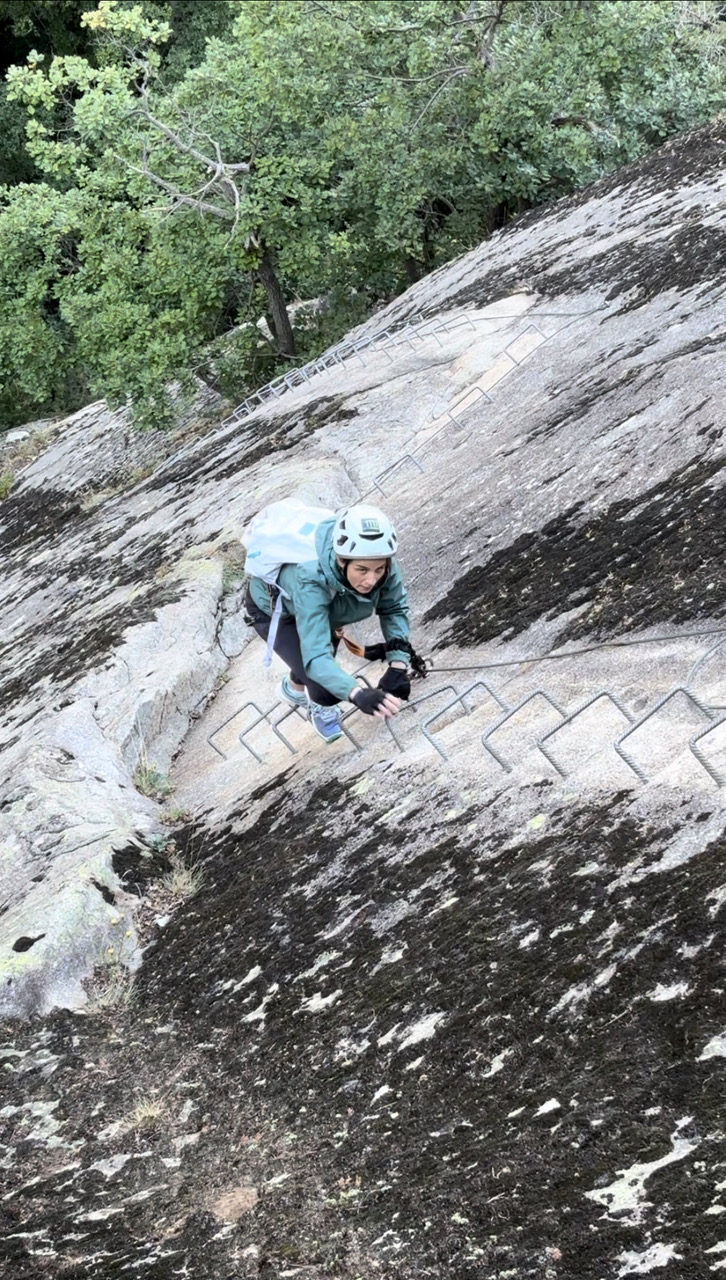 Climbing steep rock face with trees below