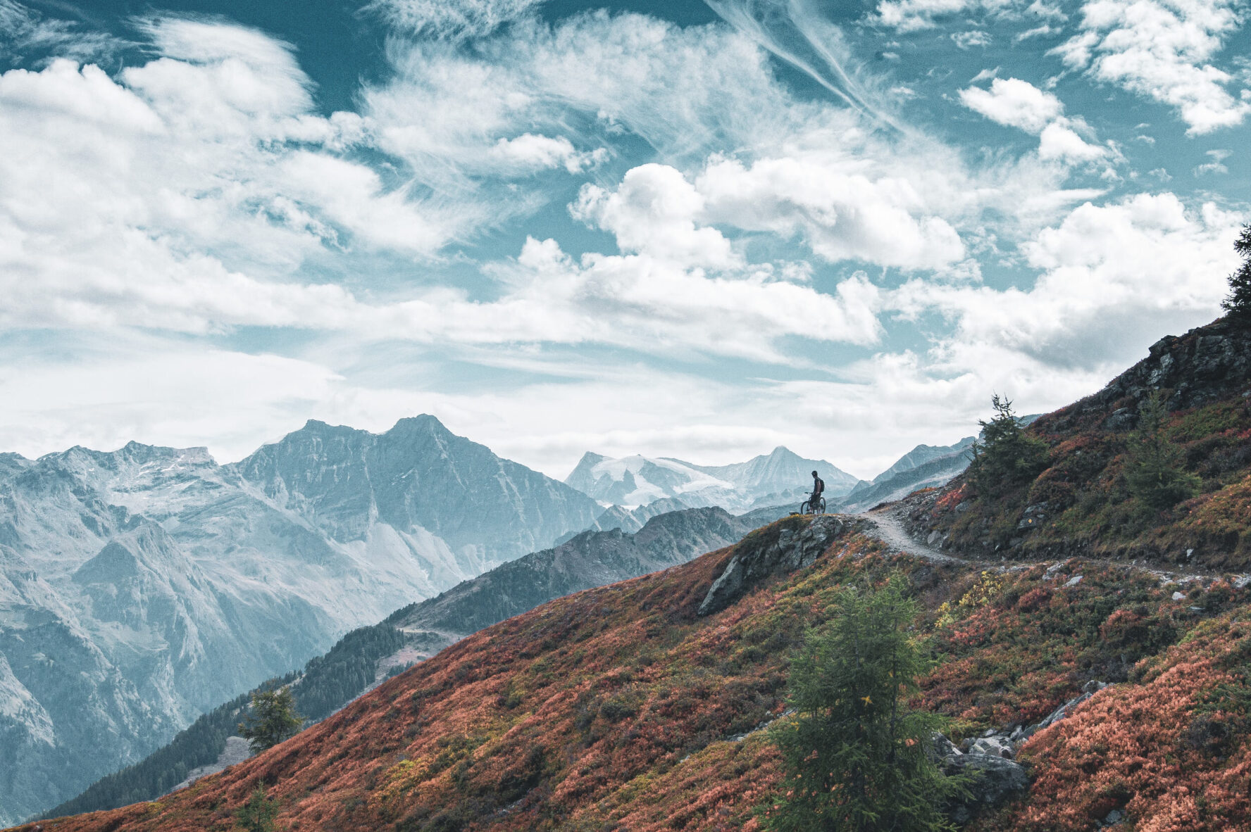 Cyclist on a trail with a scenic Alpine backdrop