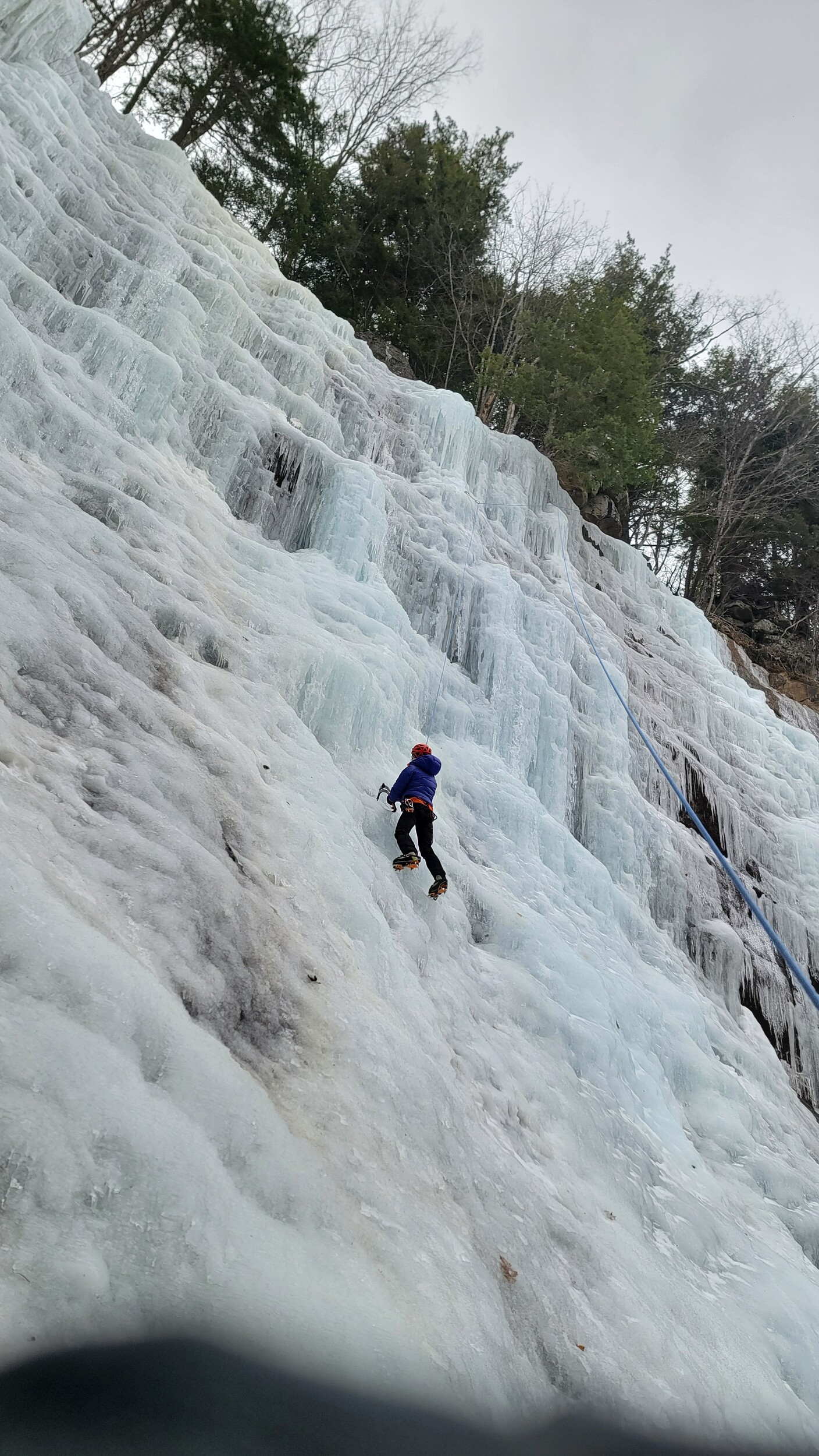 Ice climbing a vast icy cliff in New Hampshire