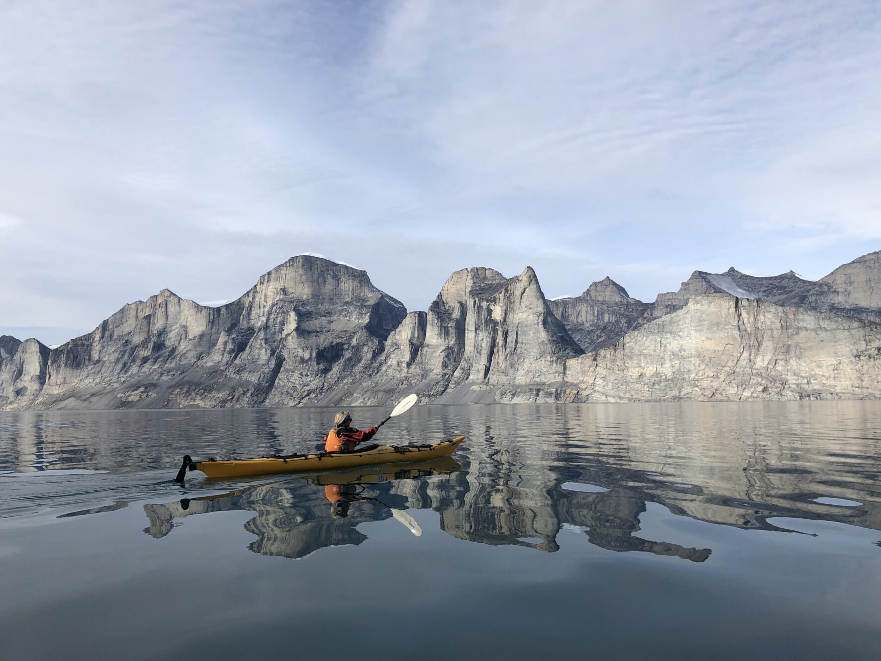 Kayak surrounded by high peaks in Baffin Island