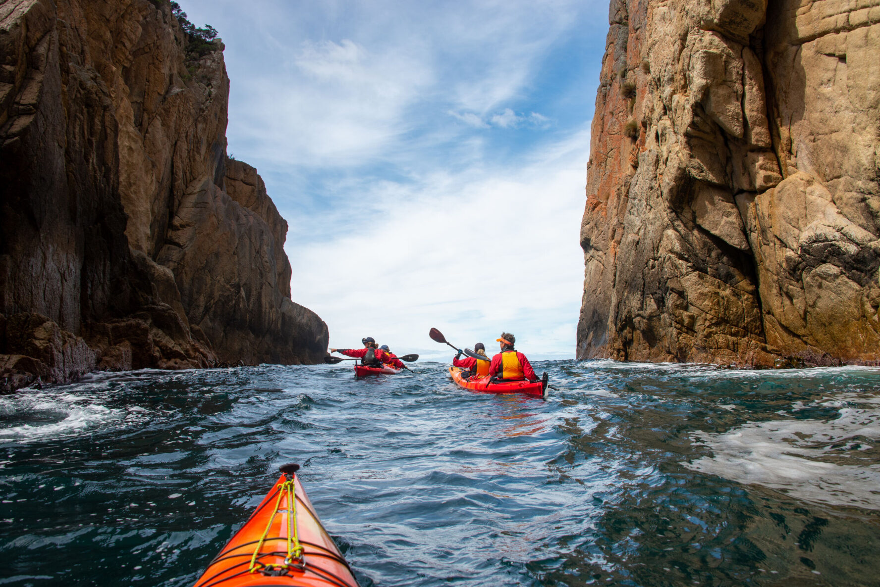 Kayakers navigating waters between towering cliff faces