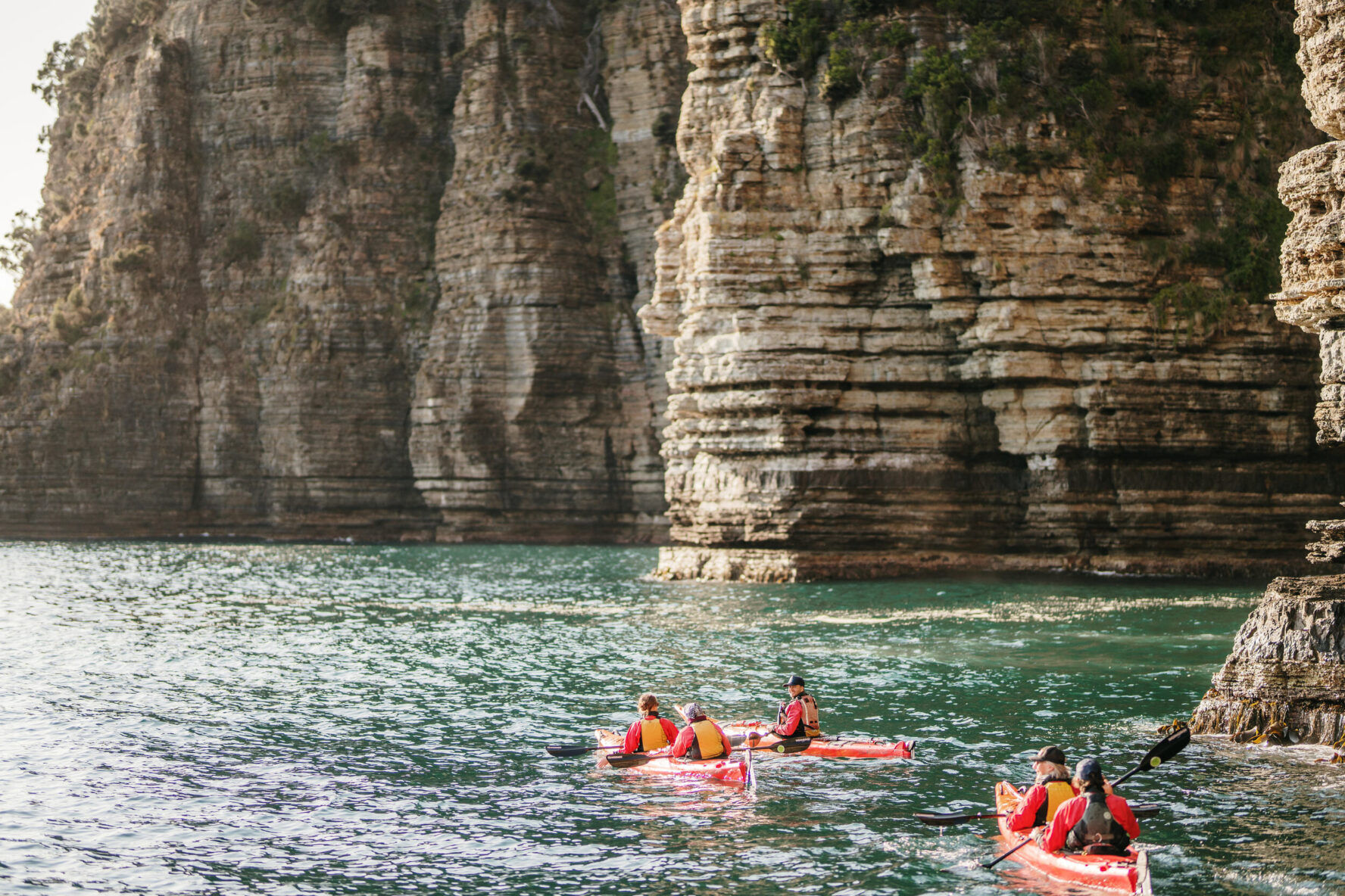 Kayakers near a rocky cliff on the Tasmanian Peninsula
