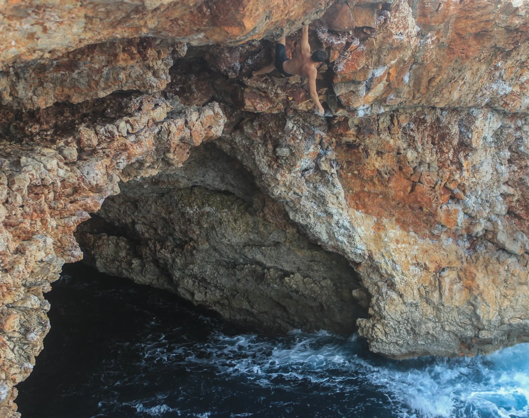 A climber doing DWS on one hand in Mallorca, Spain
