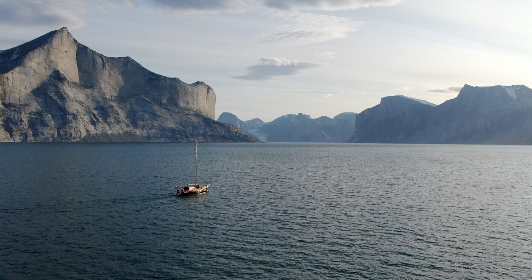 A sailboat sailing across the vast sea between Greenland and Baffin Island