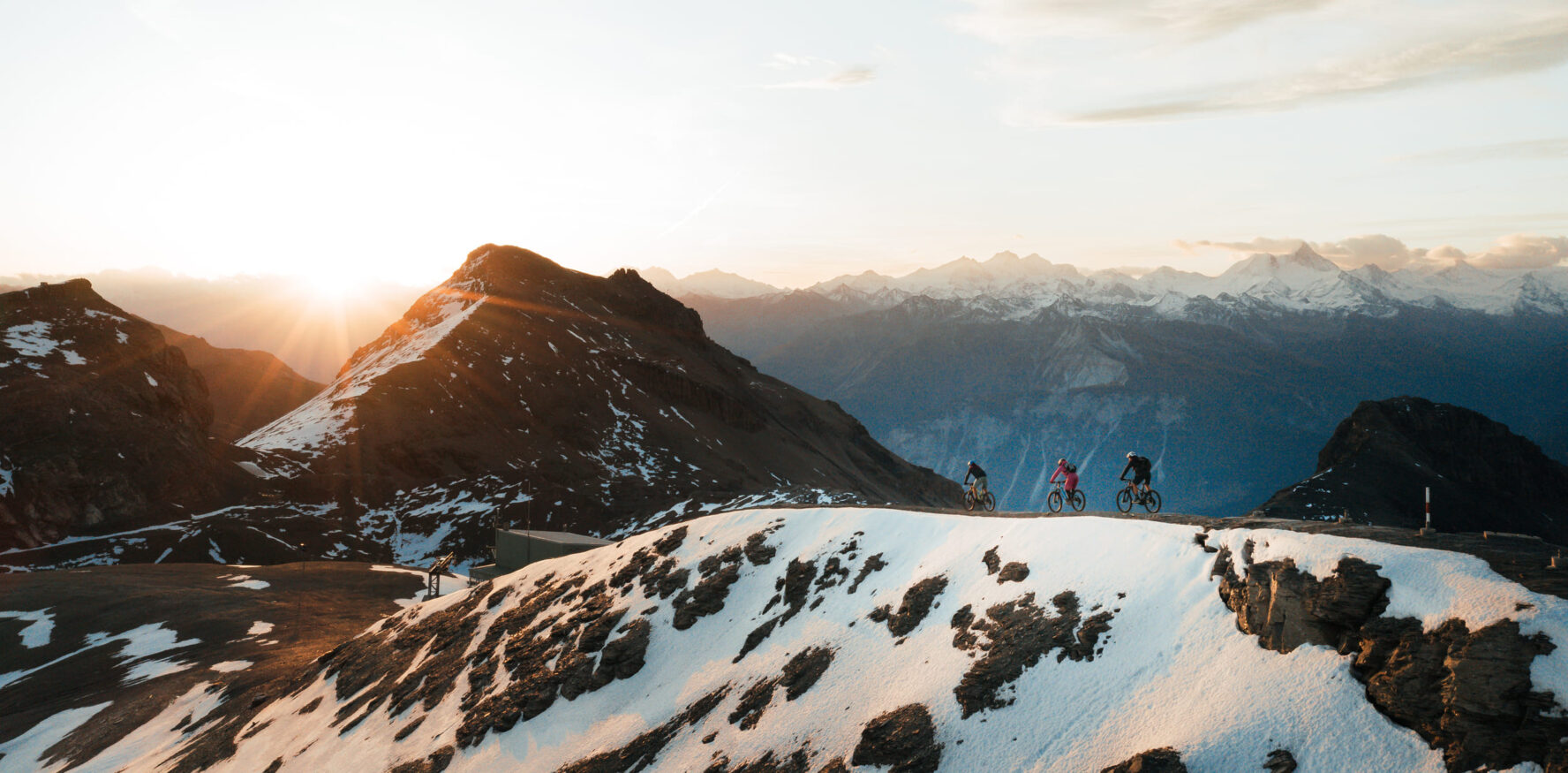 Three MTBers on a ridge in the Swiss Alps