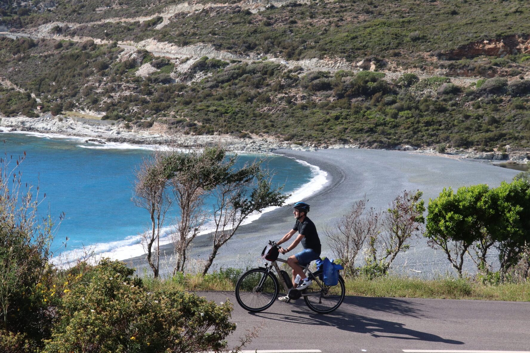 Rider on a road near a grey beach on the North Corsica bike holidays