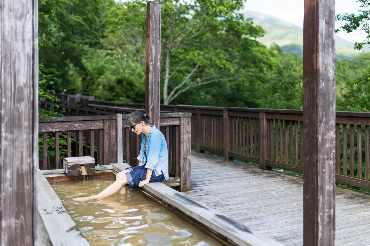 Woman soaking her legs in an outdoor Japanese foot hot spring bath