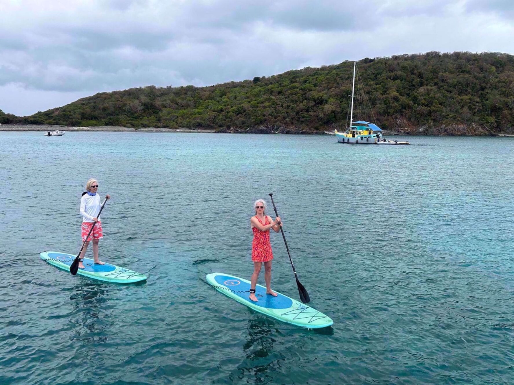 Two women stand-up paddling in a bay on St. John island in the Caribbean