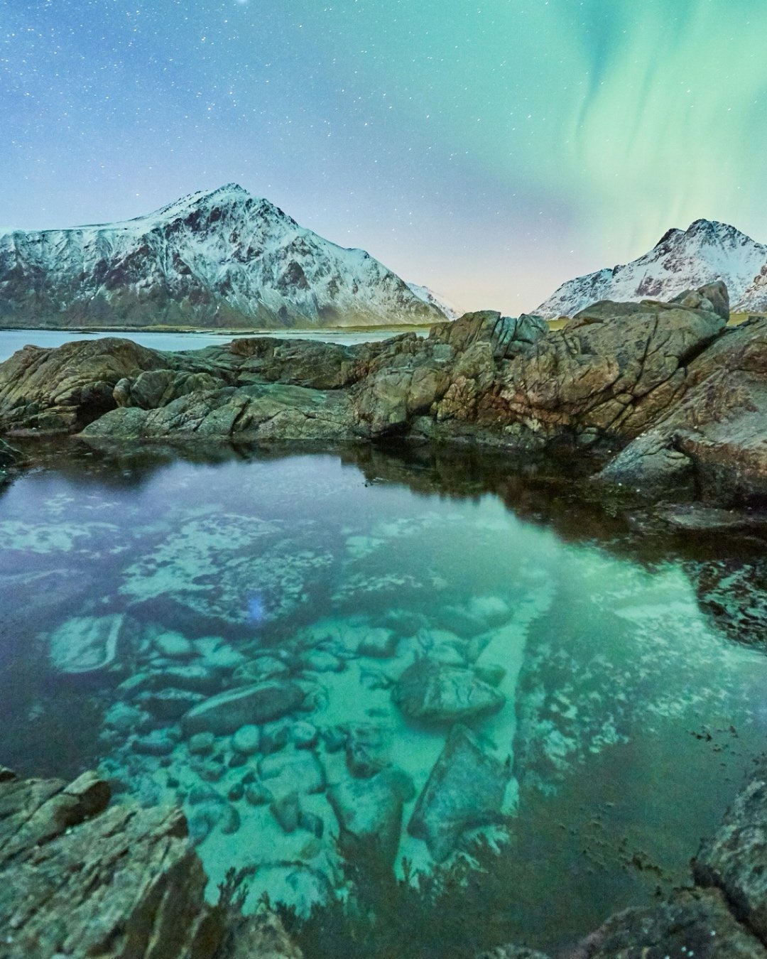 Bright Northern Lights and a clear sea while sailing Lofoten