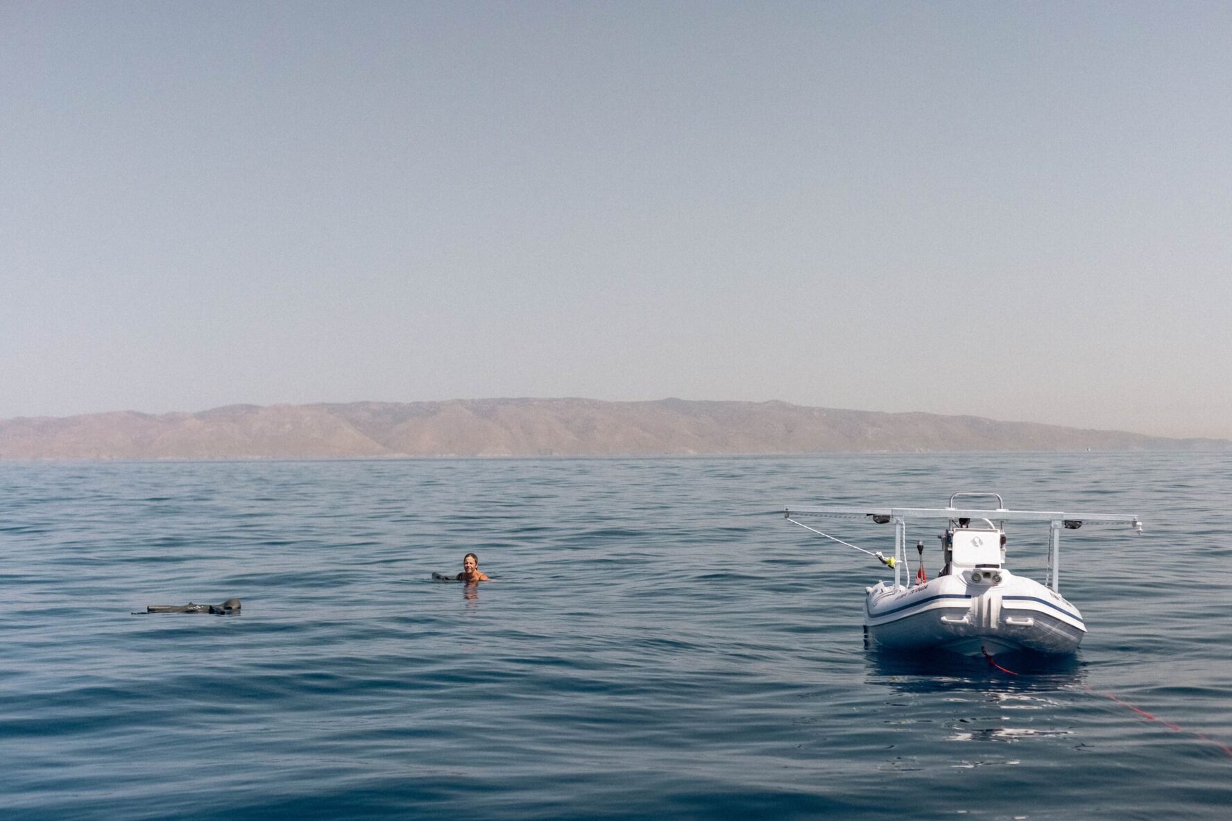 Freediver swimming near a dinghy in calm sea in Greece