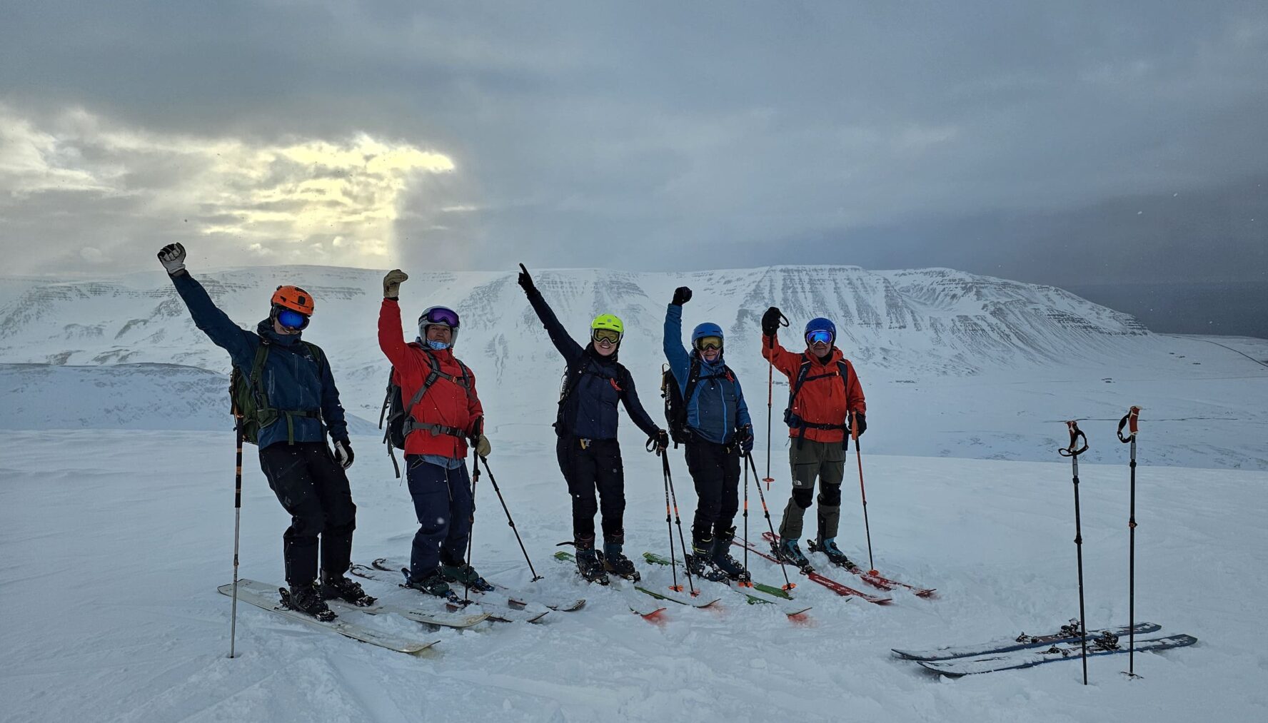 Five skiers celebrating on top of a mountain while backcountry skiing, North Iceland
