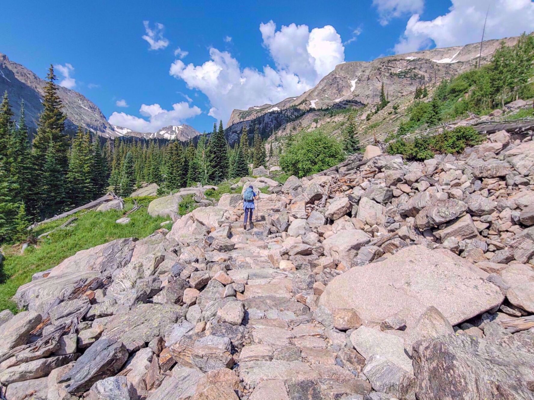 Hiker on uneven terrain with panoramic mountain views in Rocky Mountain National Park