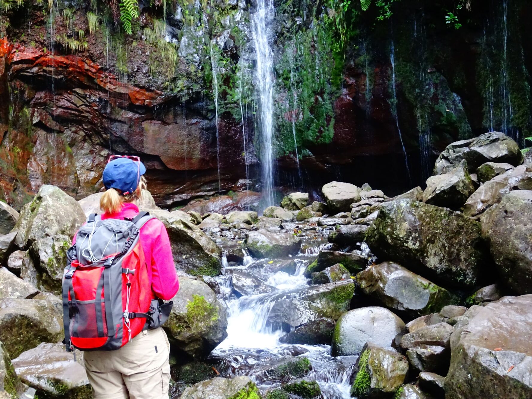 Hiker near a waterfall in a forest on the hiking tour Madeira