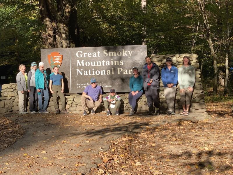 Hikers posing in front of a sign