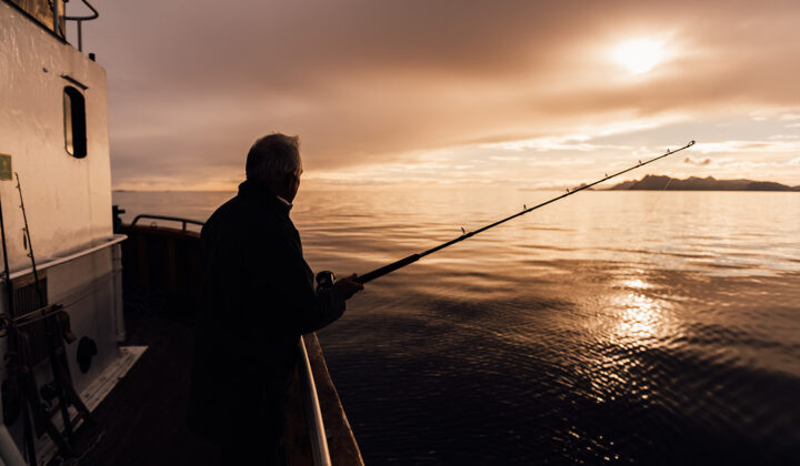 Man fishing aboard the HMS Gassten while sailing Lofoten