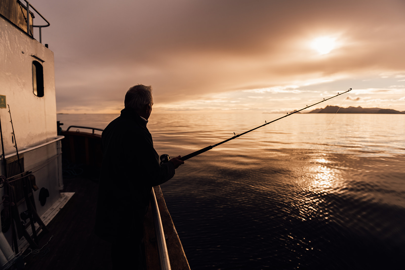 Man fishing aboard the HMS Gassten while sailing Lofoten