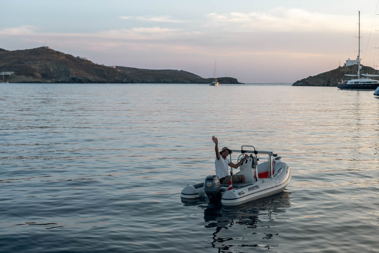 A man waving from the dinghy at sundown on the Greece freediving holiday