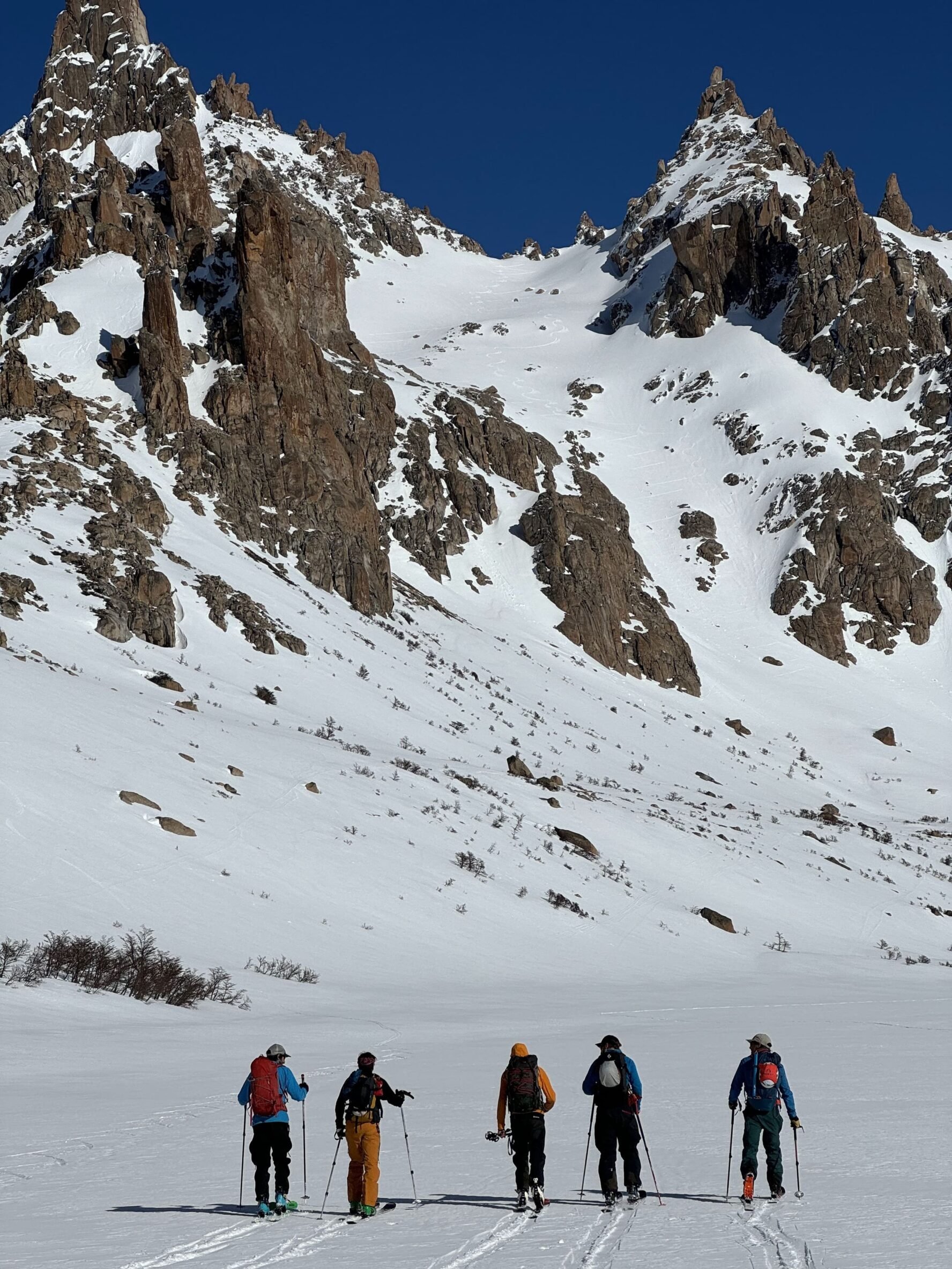 Skiers beneath a mountain