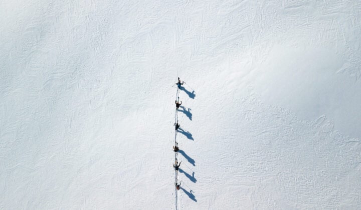Aerial shot of skiers ski touring while sailing Lofoten
