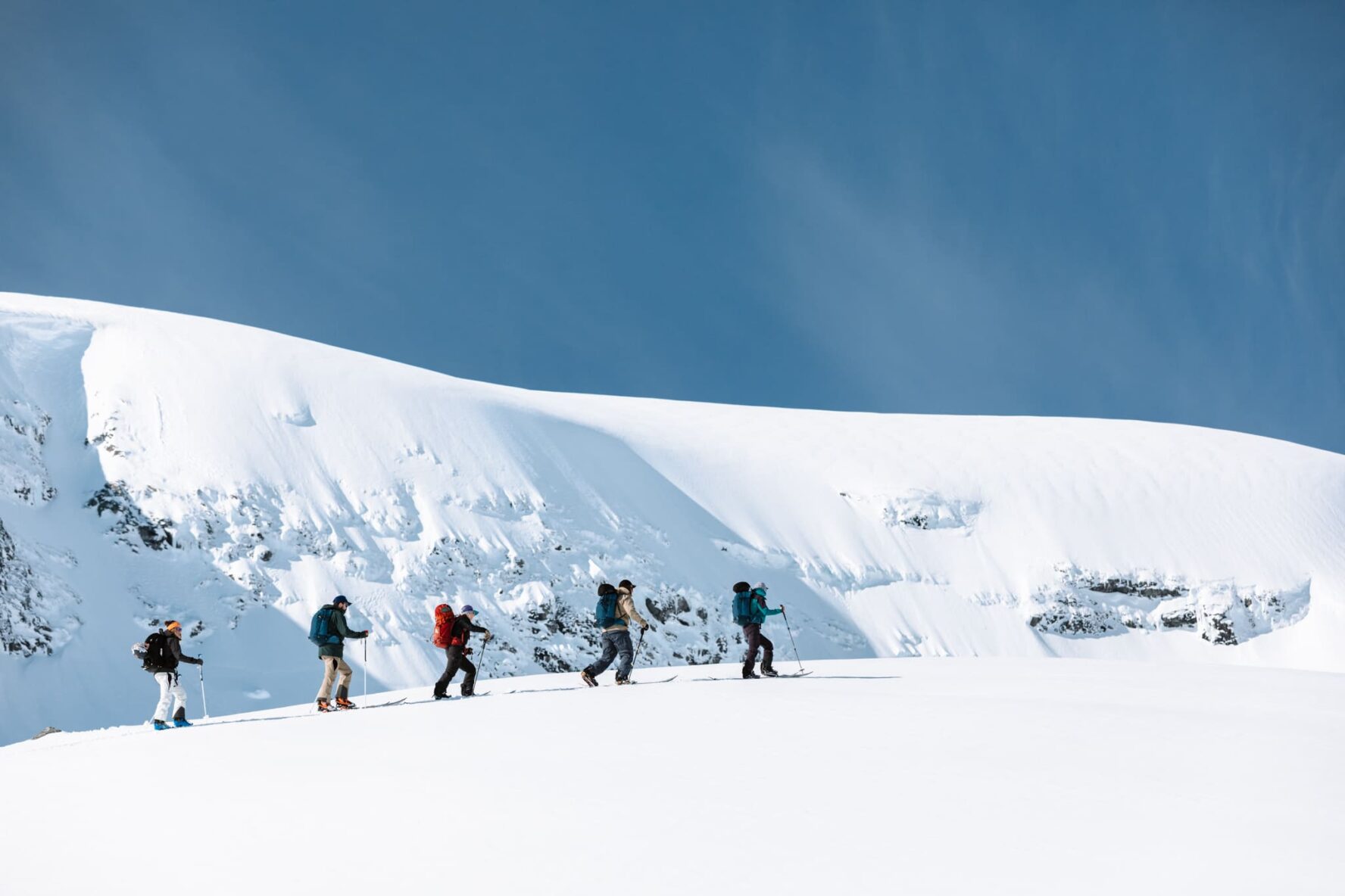 Skiers skinning up a mountain on the sailing Lofoten tour
