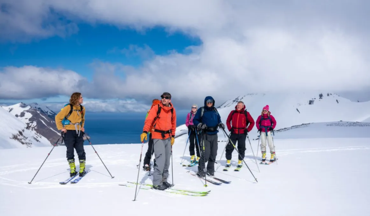Skiers on top of a mountain on a sunny day while backcountry skiing, North Iceland