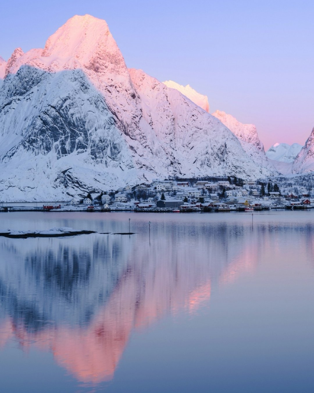 Snowy mountain lit by a pink sunset while sailing Lofoten