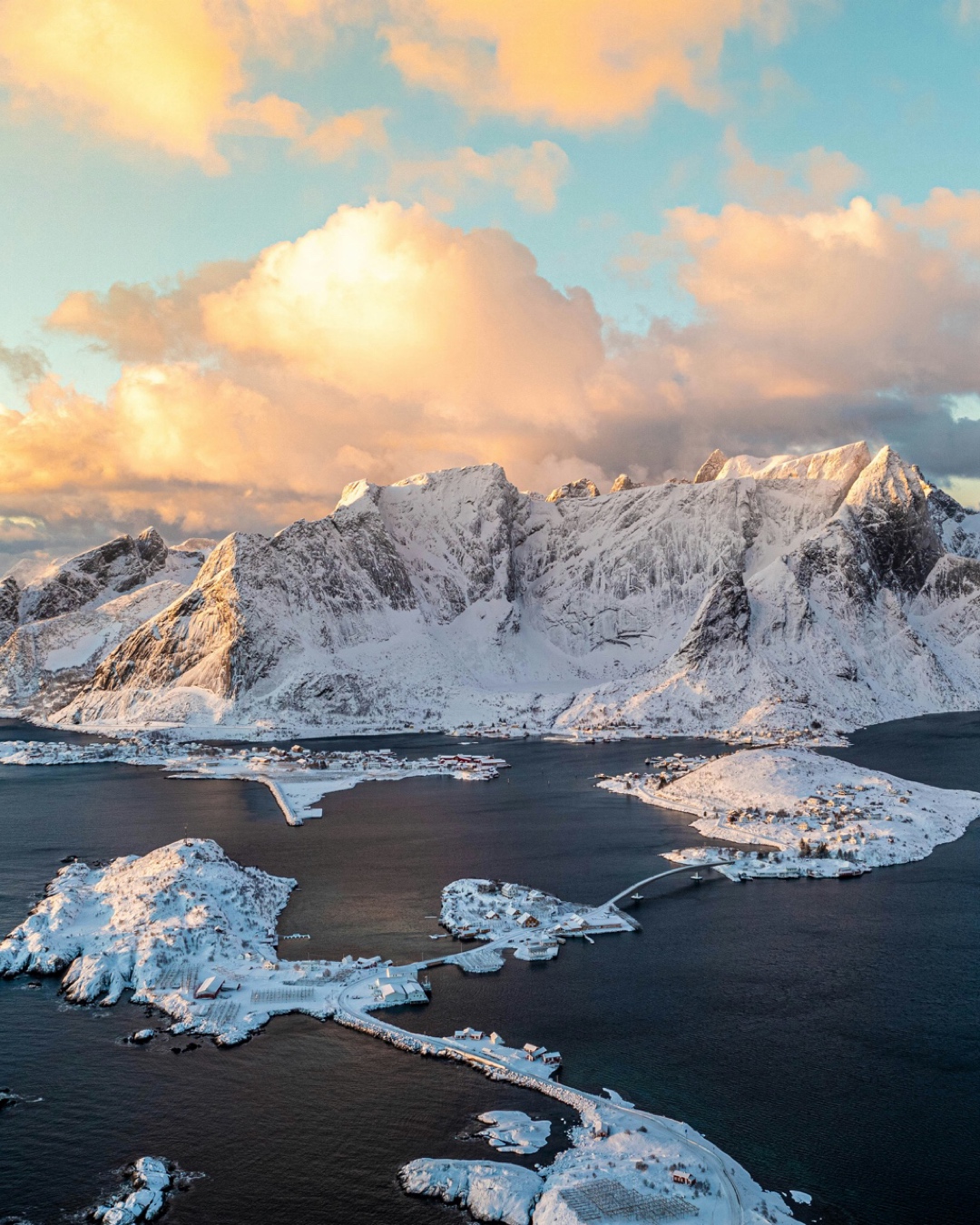 A sunlit snowy village and surrounding landscape in Lofoten
