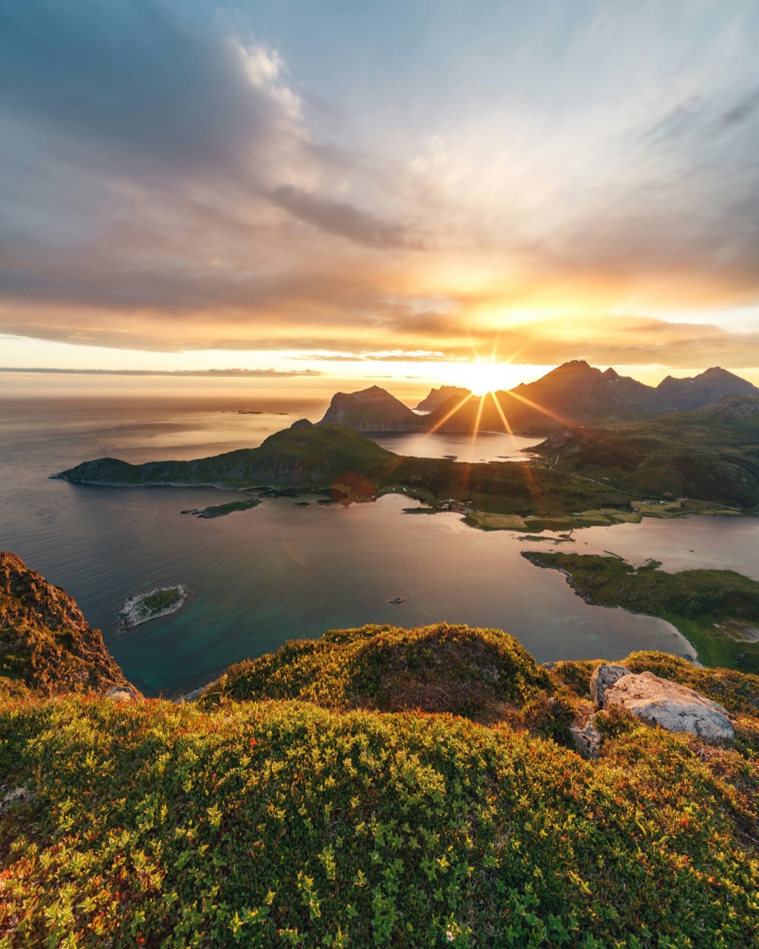 The sun illuminating a fjord and mountains from a viewpoint in Lofoten