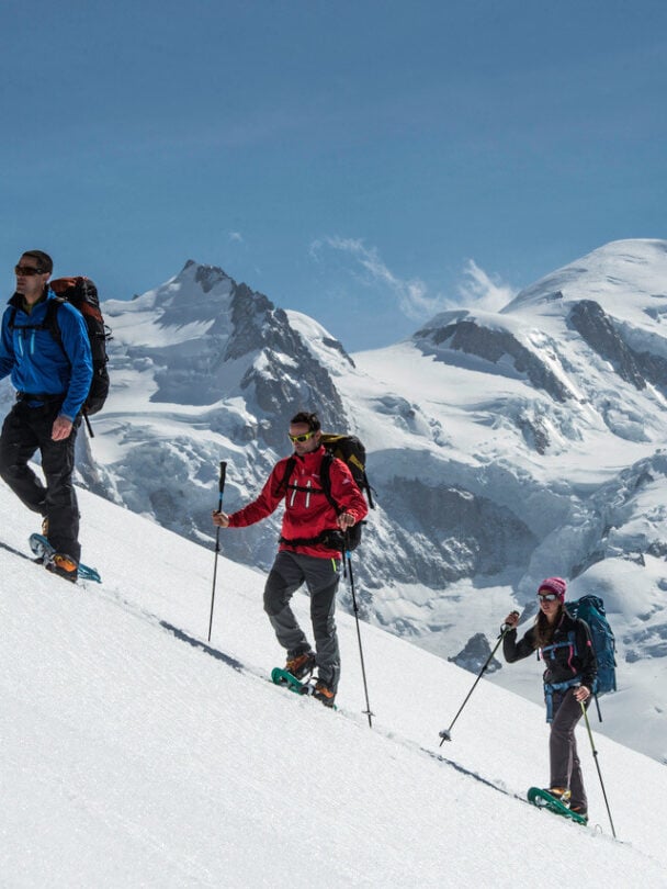 Three snowshoers ascending a mountaintop in the Chamonix area