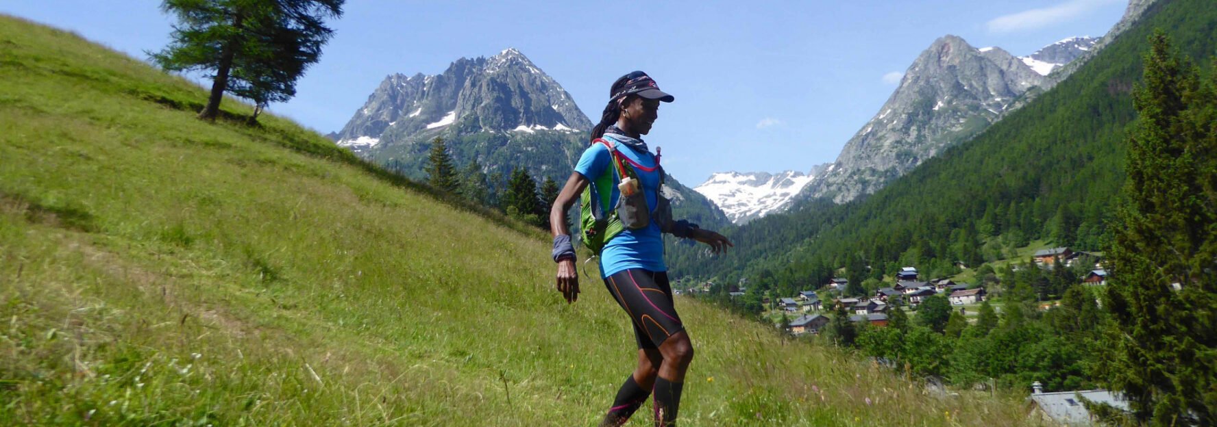 Woman trail running with mountains and an Alpine village in the background