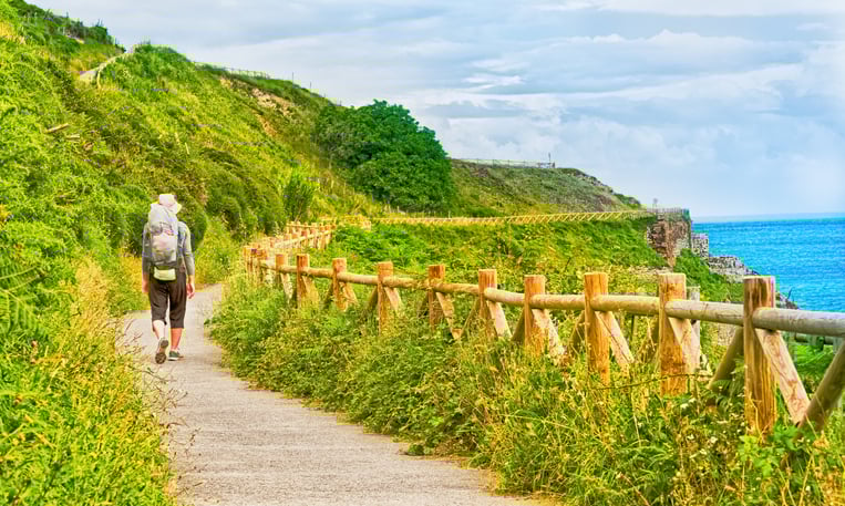 Lonely Pilgrim with backpack walking the Camino Frances seaside