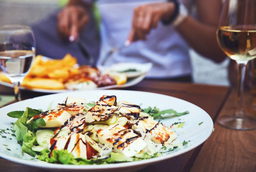 Dinner at restaurant. Close-up salad with grilled cheese. People eating on the background in Istria, Croatia