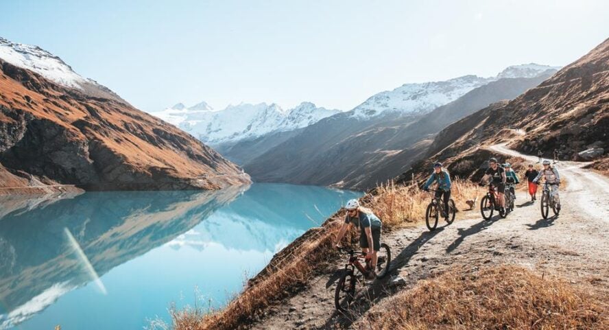 Riders biking along an alpine lake on the Haute Route 
