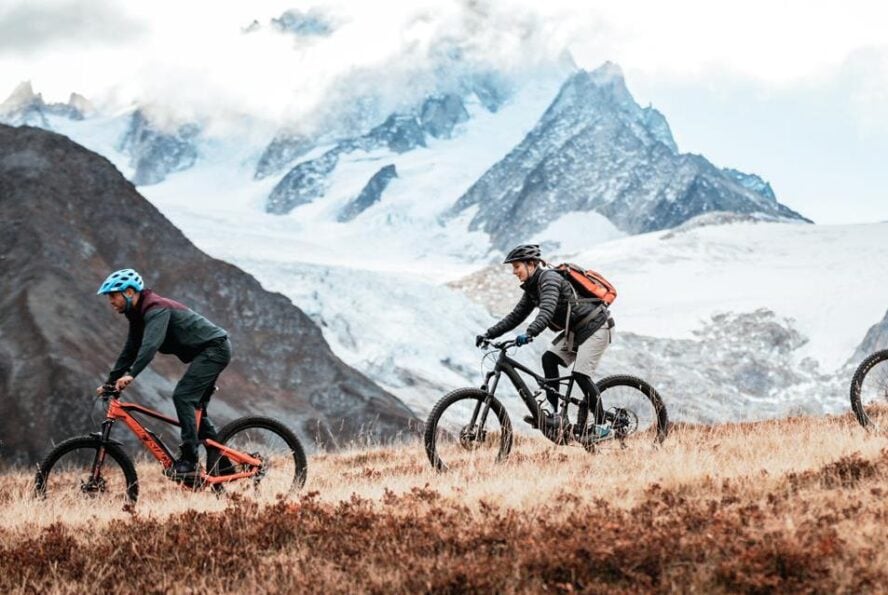 A group riding beside snow-capped peaks along the Haute Route, France