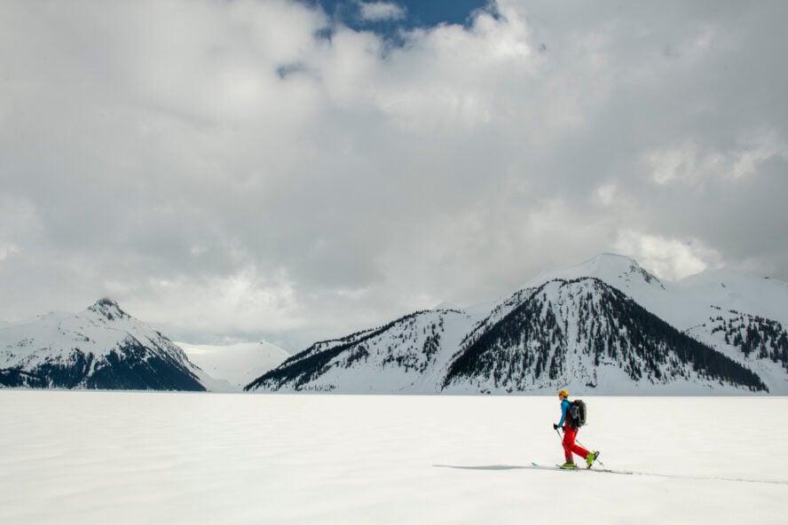 Backcountry skier skis across frozen lake