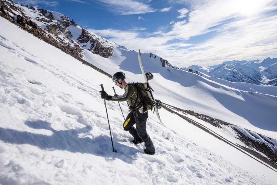 Backcountry splitboarder ascends mountain in British Columbia - What is backcountry skiing