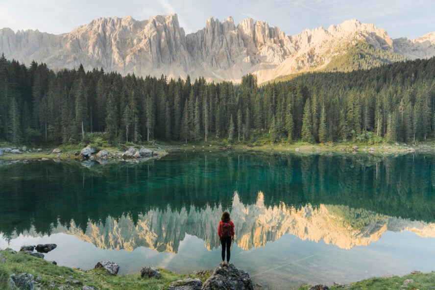 Woman standing and looking at Lago di Carezza in Dolomites along the Alta Via 1